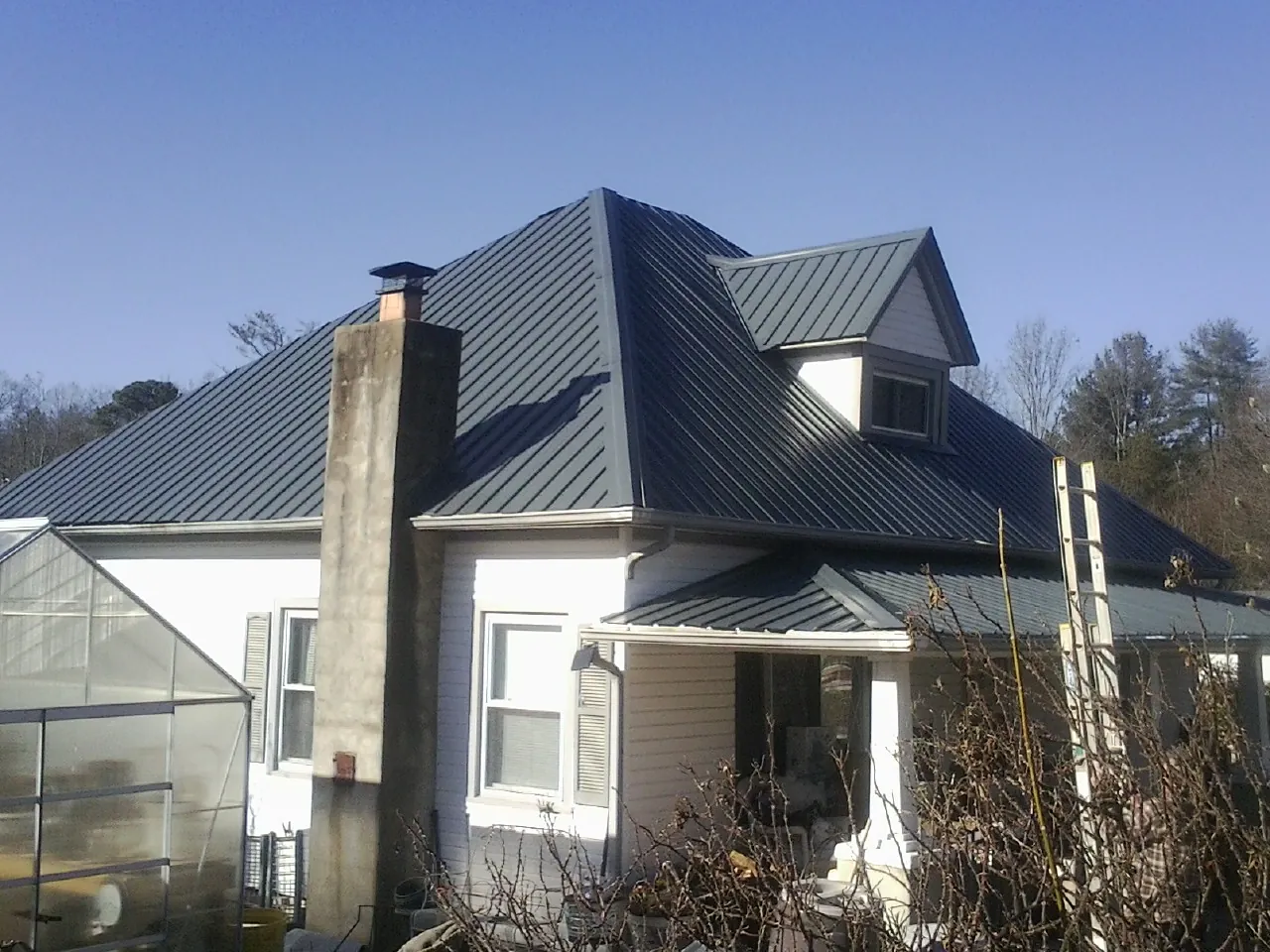 Dark blue standing seam metal roof on a white farmhouse with dormer — Slate & Tile Roof Repair by Roofing Brothers in Arlington Heights