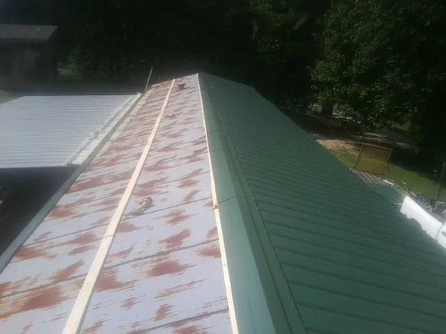 Old rusted panels beside newly installed green metal roofing — Wind Damage Roof Repair by Roofing Brothers in Arlington Heights
