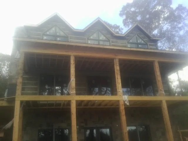Dormers and porch framing on a large log home under construction — Roof Coating work by our crew in Arlington Heights