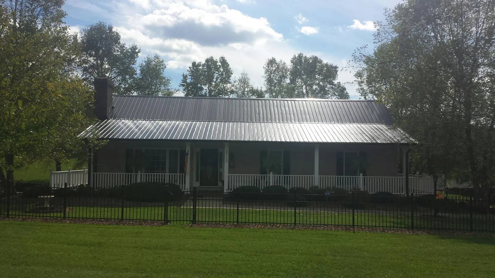 Gray metal roof on a brick ranch with a full width front porch — Gutter Guard Installation work by our crew in Arlington Heights