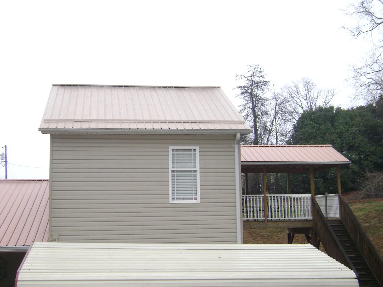 Tan metal roofs on a two story addition and attached porch, from a Roof Replacement job in Arlington Heights