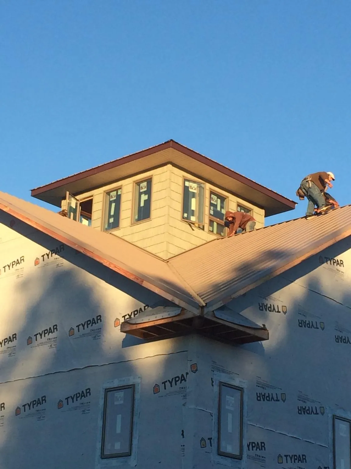 Roofers working around a rooftop cupola on a new metal roof at sunset — Roof Waterproofing in Arlington Heights by Roofing Brothers